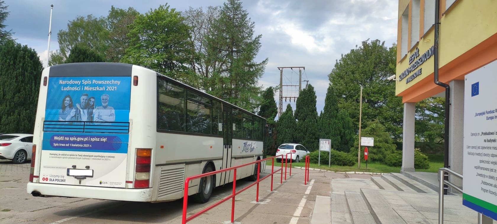 Autokar przewoźnika, na którym widnieje reklama Narodowego Spisu Powszechnego Ludności i Mieszkań 2021, zaparkowanego przy Zespole Szkolno-Przedszkolnym w Malechowie oraz Świetlicy Kultury w Malechowie. 