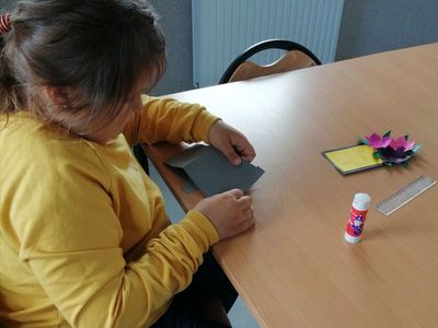 Dziewczynka z Placówki Wsparcia Dziennego w Kusicach podczas klejenia kartki.