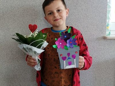 Wychowanek Placówki Wsparcia Dziennego w Kusicach  z laurką na Dzień Mamy.