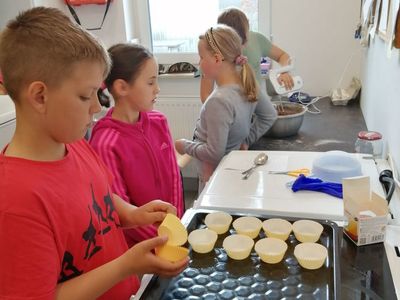 Dzieci z Placówki Wsparcia Dziennego w Kusicach pełne skupienia podczas zajęć cukierniczych.
