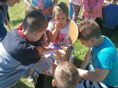 Dzieci ze Szkoły Podstawowej w Lejkowie układają układankę pod okiem nauczycielki. 