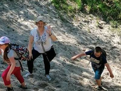 Dzieci wraz z nauczycielką ze Szkoły Podstawowej im. Kazimierza Górskiego w Lejkowie wspinają się po piaskowej górze.