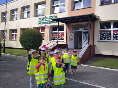 Grupa dzieci z przedszkola przy Zespole Szkół w Ostrowcu ubrana w kamizelki odblaskowe przygotowana do wyjścia poza teren przedszkola.