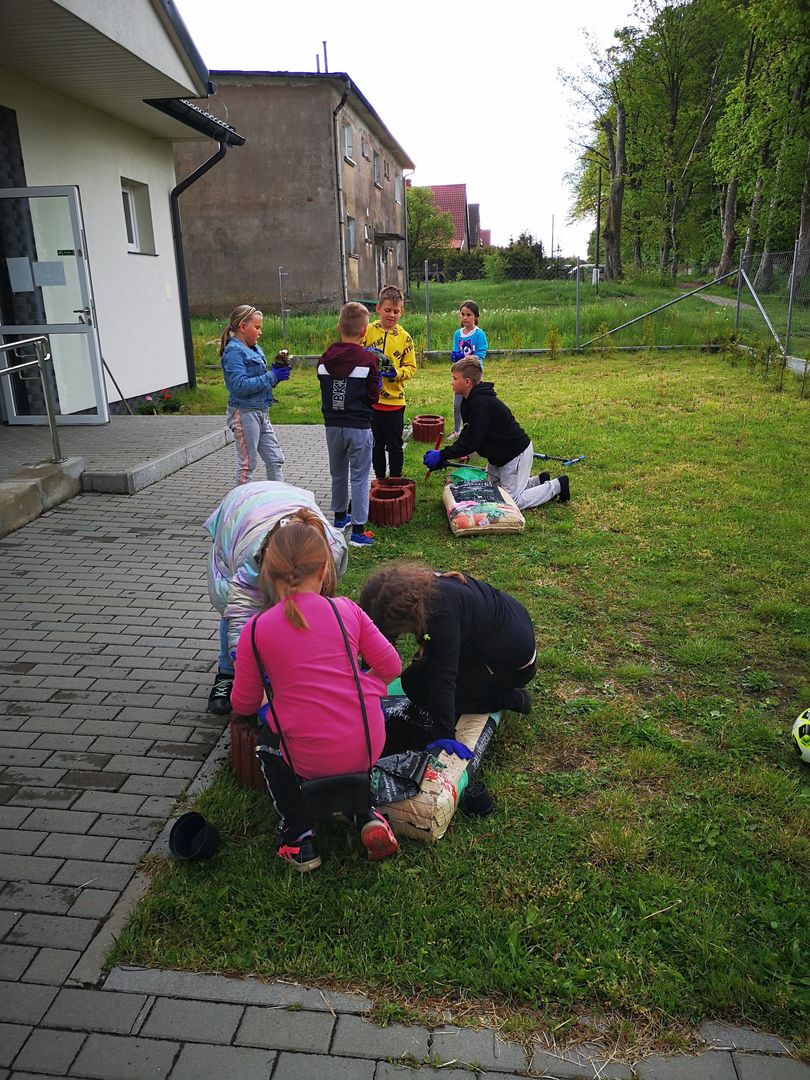 Dzieci z Placówki Wsparcia Dziennego w Kusicach dosypujące ziemię do gazonów.