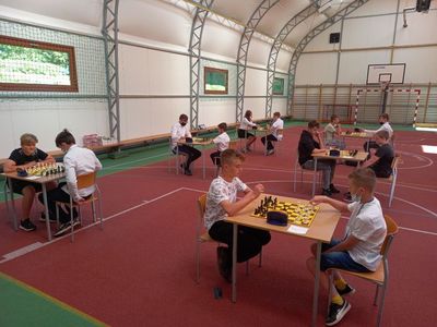 Partia szachowa, uczestnicy turnieju przy stolikach rozgrywają turniej w hali sportowej przy Szkole Podstawowej w Lejkowie.