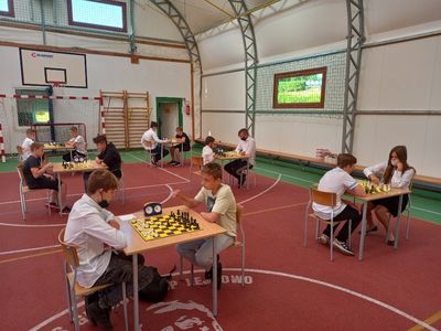 Partia szachowa, uczestnicy turnieju przy stolikach rozgrywają turniej w hali sportowej przy Szkole Podstawowej w Lejkowie. 