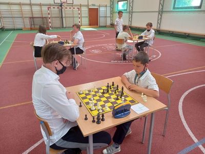 Partia szachowa, uczestnicy turnieju przy stolikach rozgrywają turniej w hali sportowej przy Szkole Podstawowej w Lejkowie. 