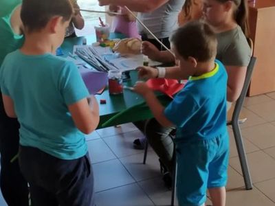 Dzieci z Placówki Wsparcia Dziennego z Lasek wykonujące wiatraki z kolorowego papieru.
