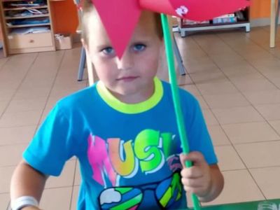 Wychowanek Placówki Wsparcia Dziennego z Lasek z wiatrakiem z papieru.
