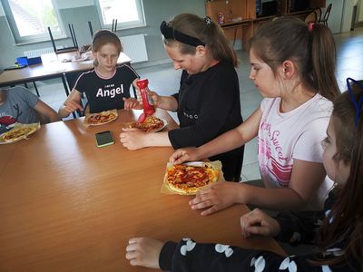 Wychowankowie z Placówki Wsparcia Dziennego w Kusicach podczas spożywania pizzy.
