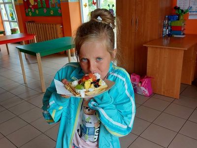 Wychowanka Placówki Wsparcia Dziennego w Laskach jedząca gofra z owocami i bitą śmietaną.
