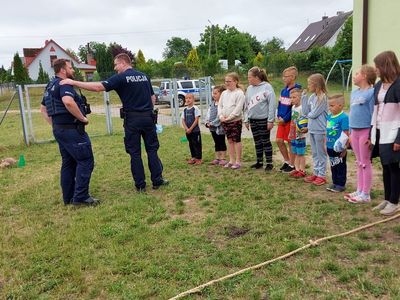 Rozpoczęcie gry w piłkę - wybieranie drużyny, dwaj policjanci i dzieci z PWD Laski w rzędzie, gotowe do rozpoczęcia gry.