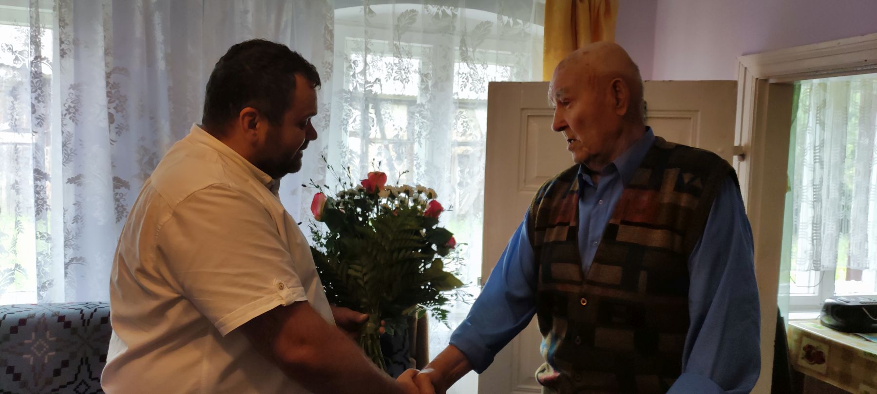 Wójt Radosław Nowakowski wręcza kwiaty 90-letniemu Józefowi Paradiukowi z Malechówka.