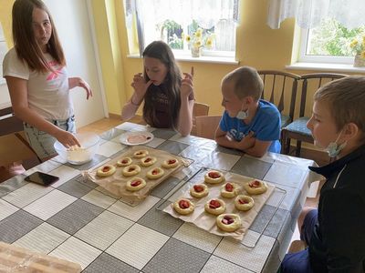 Wakacyjne zajęcia kulinarne w Placówce Wsparcia Dziennego w Święcianowie. Dzieci w trakcie wykonywania drożdżówek z truskawkami i kruszonką.