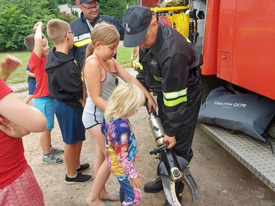 Strażacy z OSP Pękanino prezentują dzieciom sprzęt i omawiają jego przeznaczenie.