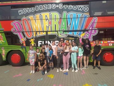 Wychowankowie wraz z wychowawczyniami z Placówki Wsparcia Dziennego w Laskach na tle kolorowego autobusu.