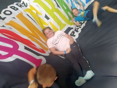 Dzieci z Placówki Wsparcia Dziennego w Laskach bawiące się na trampolinach w parku rozrywki.