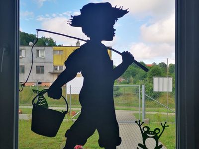Ozdobione okno, na którym jest chłopiec idący na ryby, które wykonały dzieci z Placówki Wsparcia Dziennego w Kusicach.