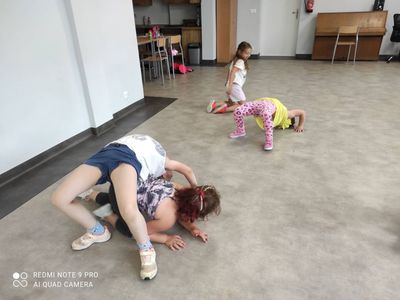 Dzieci z grupy breakdance ćwiczą mostek w sali świetlicy kultury w Malechowie.
