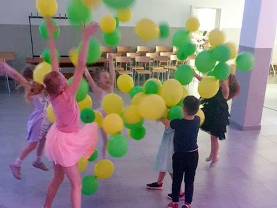 Dzieci tańczące na sali głównej Świetlicy Kultury w towarzystwie baloników.