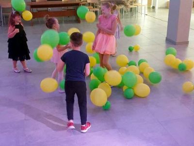 Dzieci tańczące na sali głównej Świetlicy Kultury w towarzystwie baloników. 