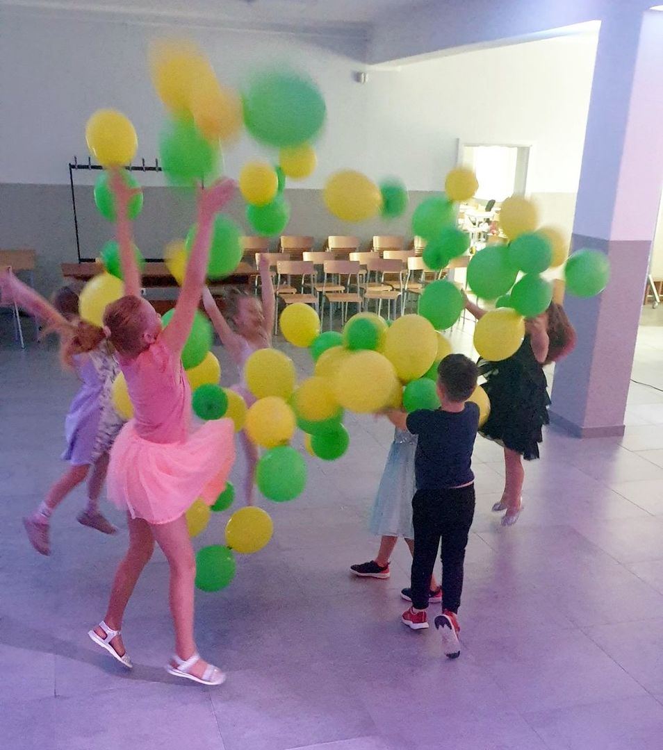 Dzieci tańczące na sali głównej Świetlicy Kultury w towarzystwie baloników.