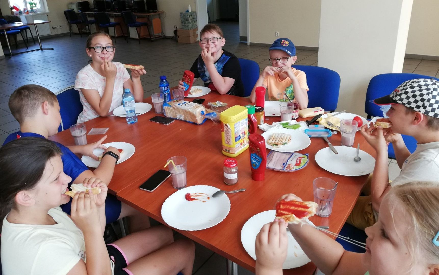 Dzieci z Placówki Wsparcia Dziennego w Pękaninie spożywają przy stole własnoręcznie wykonane tosty. 
