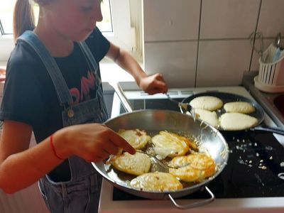 Podopieczna z Placówki Wsparcia Dziennego w Laskach w trakcie smażenia racuchów z jabłkami.  