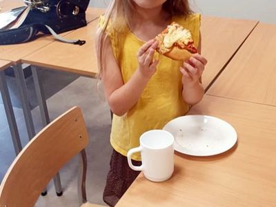 Dziewczynka z Malechowa zajada się pyszną pizzą, wykonaną podczas warsztatów kulinarnych.