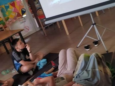 Wychowankowie z Placówki Wsparcia Dziennego w Laskach oglądają bajkę na dużym ekranie.