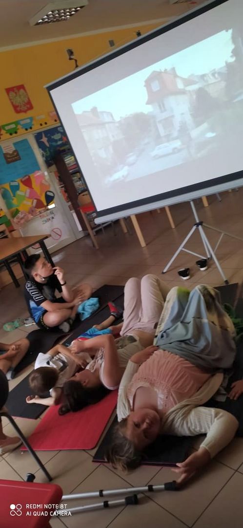 Wychowankowie z Placówki Wsparcia Dziennego w Laskach oglądają bajkę na dużym ekranie.