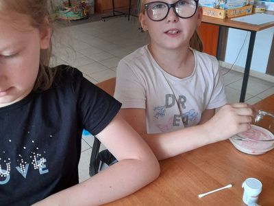 Dwie dziewczynki z Placówki Wsparcia Dziennego w Sulechowie wsypują barwniki spożywcze do mleka.