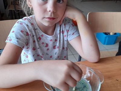 Dziewczynka z Placówki Wsparcia Dziennego w Sulechowie mieszająca barwnik z mlekiem.