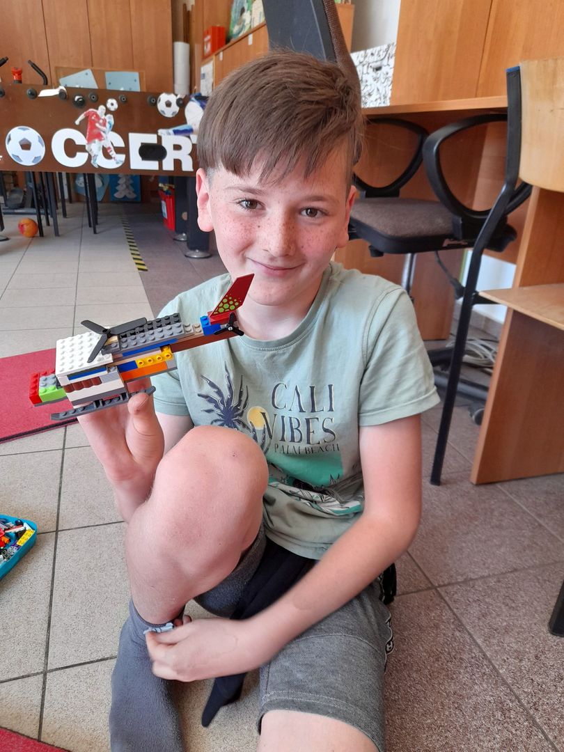 Chłopiec z Placówki Wsparcia Dziennego w Sulechowie pozujący z helikopterem zbudowanym z klocków Lego.