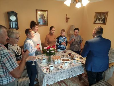 Wójt Radosław Nowakowski i 95-letnia Genowefa Góraj oraz jej rodzina śpiewają Dwieście Lat przy symbolicznej lampce szampana.  