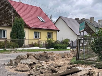 Rozebrana część drogi i chodnika, widoczne płyty.