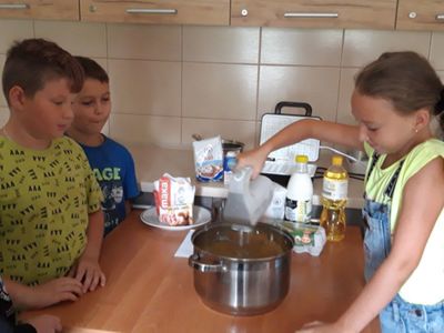 Dziewczynka z Placówki Wsparcia Dziennego w Kosierzewie przy użycia miksera wyrabia ciasto na gofry.