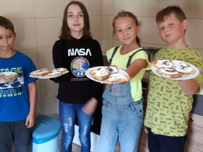Dzieci z Placówki Wsparcia Dziennego w Kosierzewie prezentują upieczone gofry z bitą śmietaną i posypką.