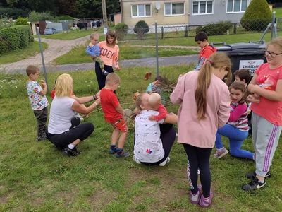 Dzieci i ich rodzice z Lasek pieką kiełbaski. 
