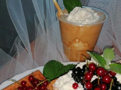 Gofry ozdobione bitą śmietaną i kawa mrożona w tle. 