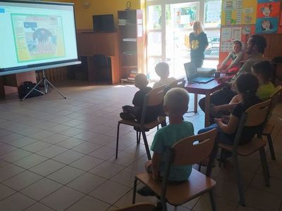 Dzieci z Placówki Wsparcia Dziennego w Laskach oglądają prezentację multimedialną przygotowaną przez myśliwego.
