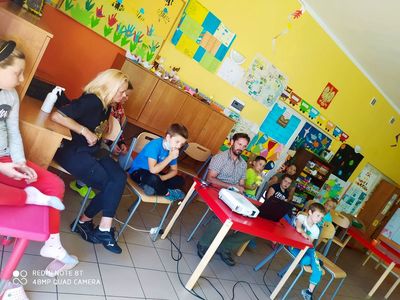Dzieci z Placówki Wsparcia Dziennego w Laskach oglądają prezentację multimedialną przygotowaną przez myśliwego.
