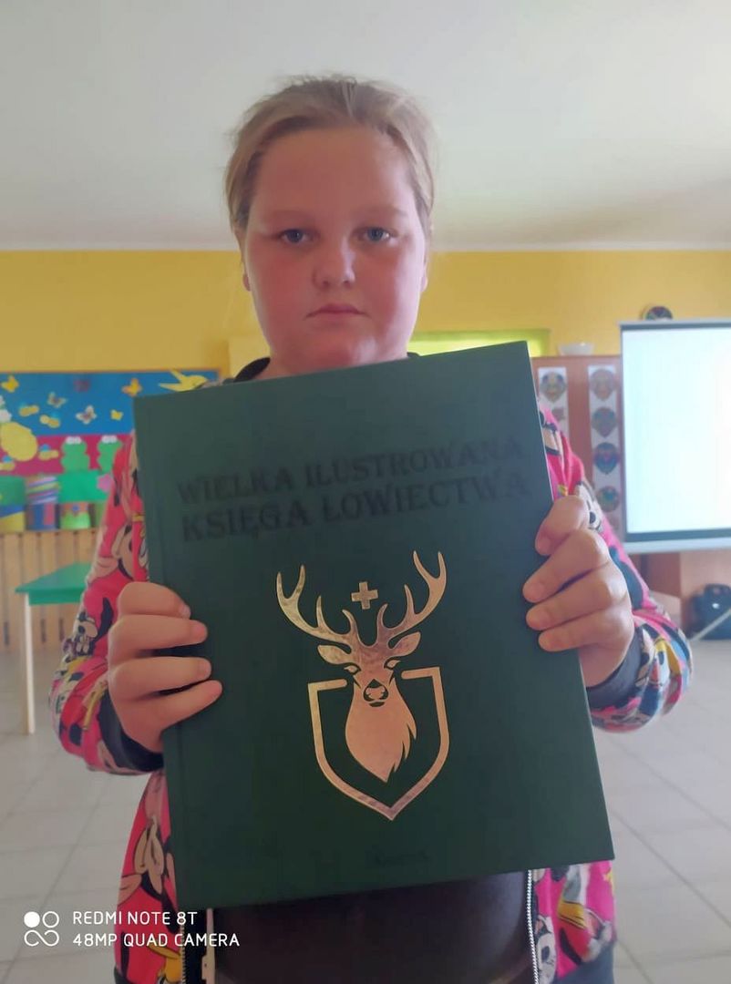 Dziewczynka z Placówki Wsparcia Dziennego w Laskach z Księgą Łowiecką.