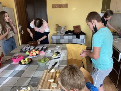 Dzieci z Placówki Wsparcia Dziennego w Święcianowie w trakcie wykładania ciasta na muffinki oraz przygotowywania owoców do sałatki.