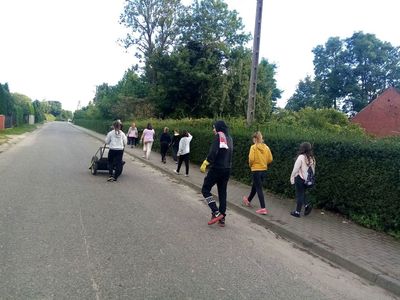 Dzieci z Karwic spacerują po wsi wzdłuż chodnika i zbierają śmieci.