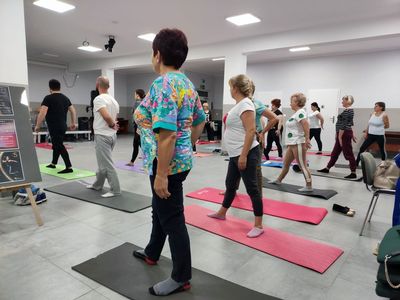 Uczestnicy zajęć jogi ćwiczą w sali głównej Świetlicy Kultury w Malechowie. 