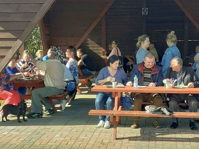 Osoby uczestniczące w festynie biesiadują przy ławostołach.