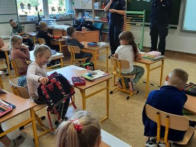 Dwie policjantki rozmawiają z uczniami klasy pierwszej na temat bezpieczeństwa w Szkole Podstawowej w Malechowie. 