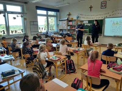 Dwie policjantki rozmawiają z uczniami klasy pierwszej na temat bezpieczeństwa w Szkole Podstawowej w Malechowie. 