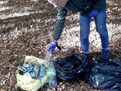 Uczeń ze Szkoły Podstawowej w Malechowie sprząta śmieci i wrzuca je do worka.